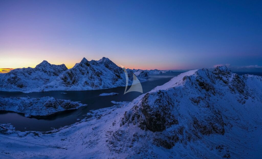 Snow-covered peaks above the sea at blue hour in northern Norway